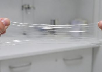 Amostra de plástico é puxada com força sem rasgar em ambiente de laboratório.