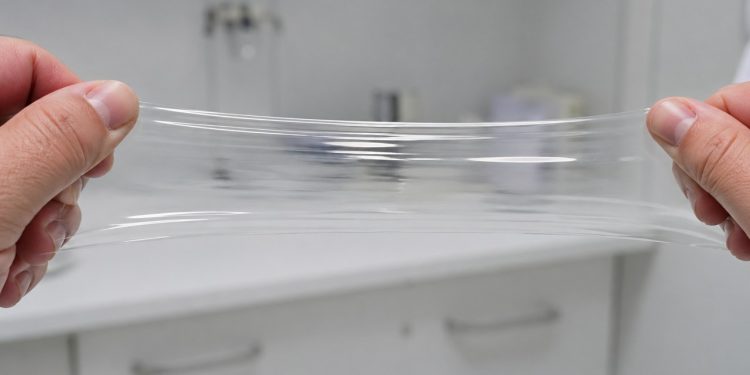Amostra de plástico é puxada com força sem rasgar em ambiente de laboratório.