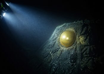 Orbe dourado aparece preso a uma rocha no fundo do oceano durante exploração submarina.