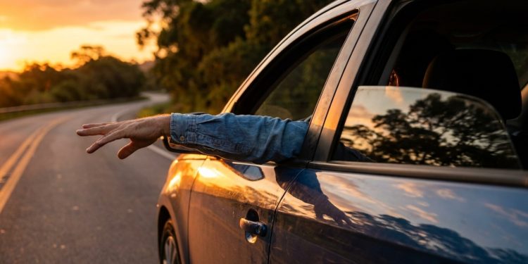 Quem viaja pelas rodovias brasileiras já deve ter visto o gesto: um motorista com o braço para fora do carro, mão aberta em posição baixa, movendo suavemente para cima e para baixo