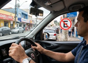 Motorista interpreta placa de regulamentação antes de seguir em uma via urbana.