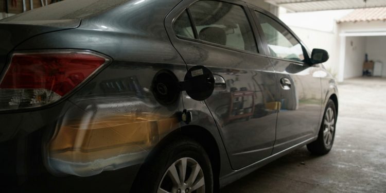 Carro flex parado em garagem com tanque em corte visual, etanol armazenado e gotas de umidade no interior