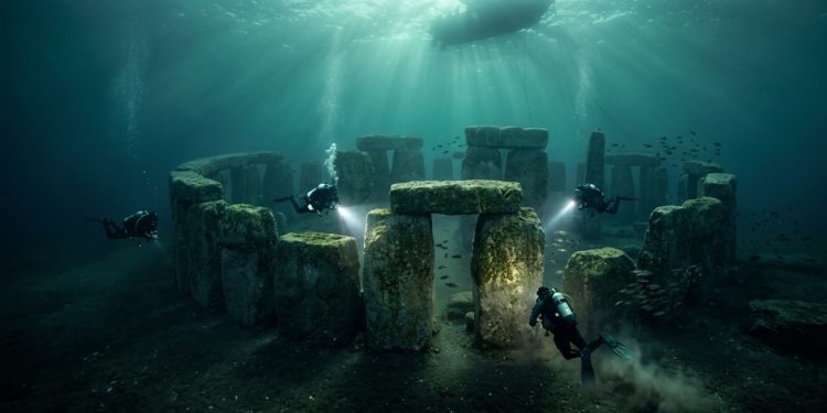 Mergulhadores exploram estruturas de pedra submersas semelhantes a monumentos antigos, iluminadas por feixes de luz vindos da superfície.