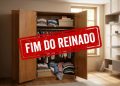 Guarda-roupa antigo de madeira aberto em uma sala, com roupas organizadas e carimbo vermelho escrito “Fim do reinado”.