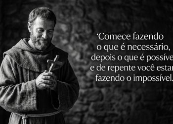 Homem com hábito religioso segura uma cruz de madeira, ao lado de uma frase motivacional sobre começar pelo necessário e alcançar o impossível.