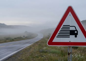O que indica a placa de trânsito com um carro entre listras pretas dentro de um triângulo vermelho?