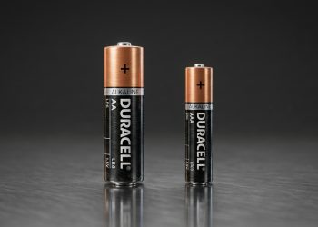 Pilhas alcalinas AA e AAA lado a lado sobre superfície escura, mostrando diferença de tamanho entre os dois modelos.