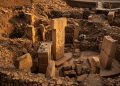 Representação de escavação arqueológica em Göbekli Tepe, na Turquia, com pilares de pedra esculpidos e estruturas circulares antigas.