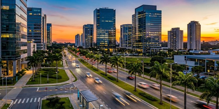 Avenida moderna em Barueri ao entardecer, com prédios comerciais, palmeiras, carros em movimento e céu colorido.