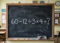 Lousa negra tradicional de sala de aula com a borda de madeira. No centro, escrito em giz branco, a expressão "60 - 12 ÷ 3 x 4 = ?". Um apagador e pedaços de giz estão apoiados na base da lousa. Ao fundo, desfocadas, veem-se carteiras escolares vazias.