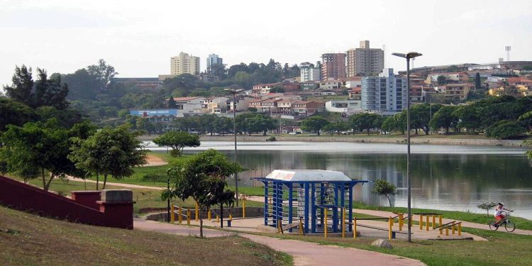 Vista de parque urbano com lago, ciclovia, árvores e prédios ao fundo, em cenário tranquilo de cidade do interior paulista.