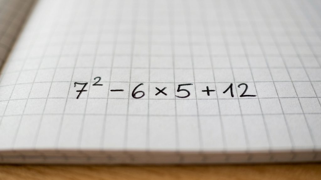 Caderno quadriculado com a expressão matemática 7² - 6 × 5 + 12 escrita à mão.