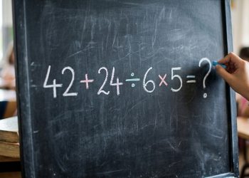 Expressão matemática 42 + 24 ÷ 6 × 5 = ? escrita em uma lousa escolar, com mão segurando giz e sala de aula ao fundo.