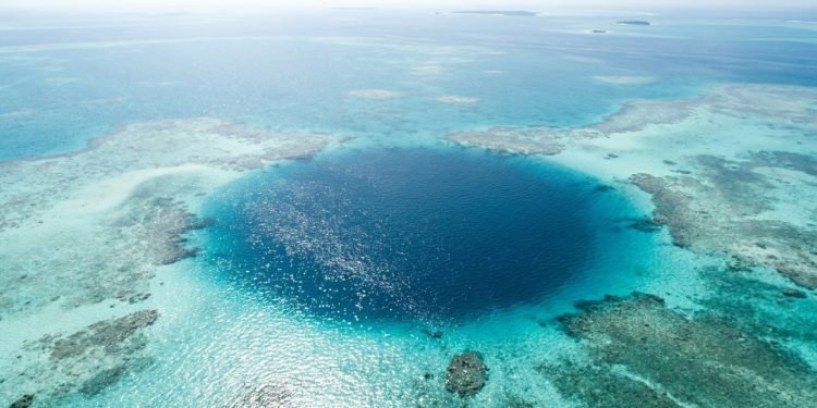 Buraco azul escuro surge no recife tropical como uma fenda profunda no mar