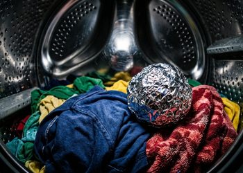 Bola de papel-alumínio sobre roupas coloridas dentro de máquina de lavar, em cena associada a truques de lavanderia.