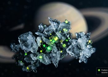 Ilustração macro de grãos de gelo flutuando no espaço sideral com pontos verdes brilhantes indicando a presença de fósforo. Ao fundo, o planeta Saturno aparece levemente desfocado. No canto inferior direito, uma pequena caixa de texto diz: 'Fósforo detectado no oceano de Encélado'.