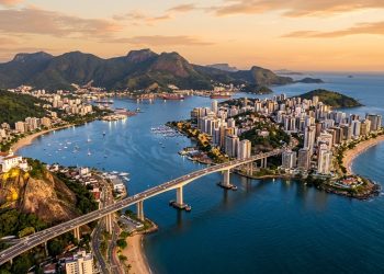 Vista aérea de Vitória, no Espírito Santo, com a Terceira Ponte, mar, prédios, praias e montanhas ao fundo