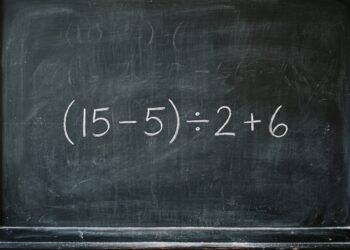 Lousa negra tradicional exibindo a expressão "(15 - 5) ÷ 2 + 6" escrita de forma centralizada com giz branco. O quadro apresenta algumas marcas suaves de giz apagado ao fundo.