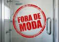 Box de banheiro com carimbo vermelho “fora de moda” sobre o vidro, em imagem associada a tendências de decoração e reforma.