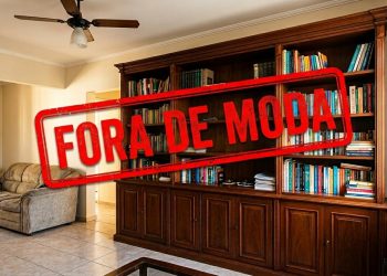 Sala de estar com estante de livros e móveis de madeira, marcada por um grande selo vermelho com a frase “Fora de moda”.